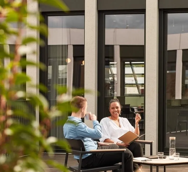 Two colleagues talking on a sunny office terrace